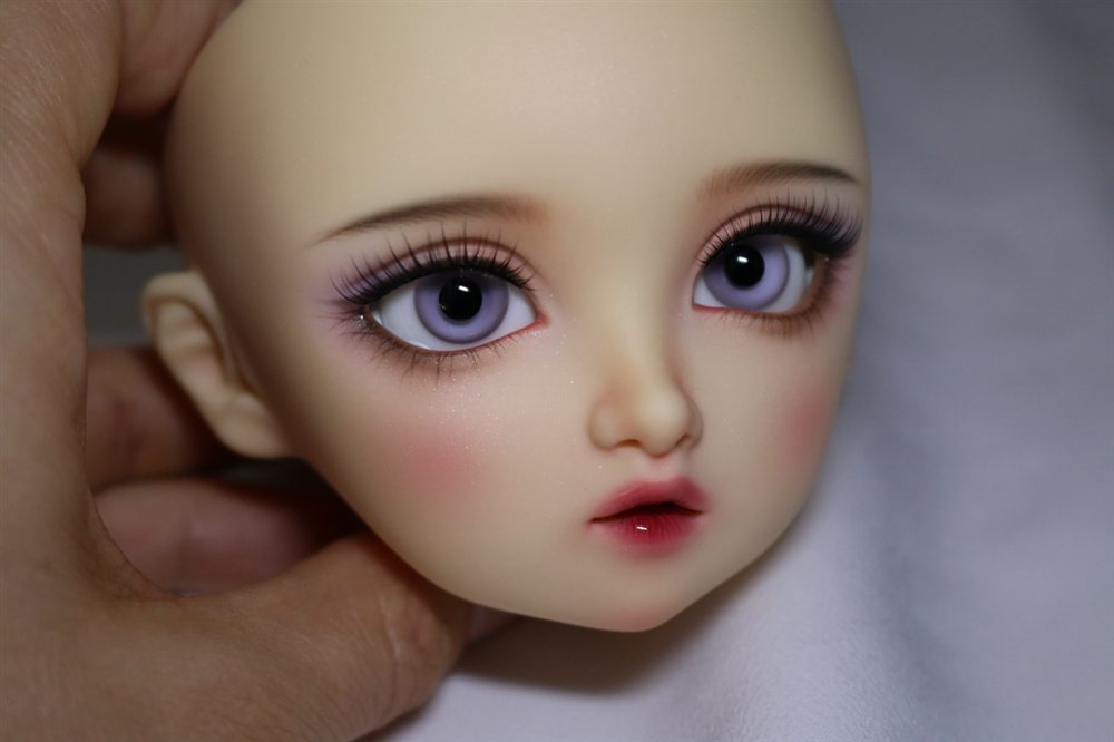 Doll face-up with violet eyes, purple eyeshadow, long lashes, rosy cheeks and a deep red glossy lip.