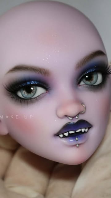 Fantasy face-up on a lilac doll: blue glitter eyeshadow, dark lips, fangs, a nose ring and lip piercings.