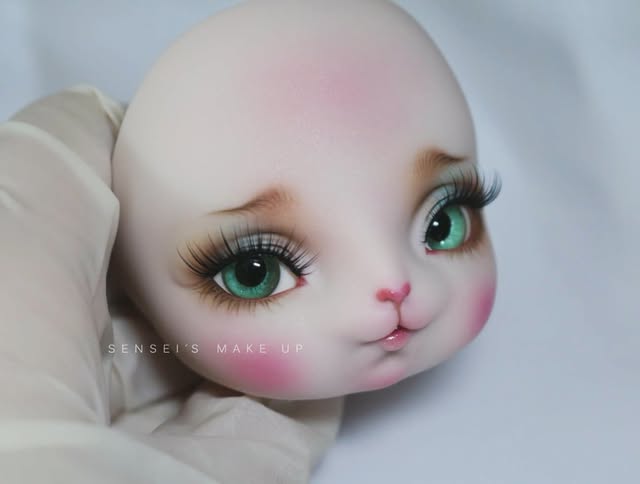 Cute animal-like doll face with mint green eyes, strong pink blush and a tiny pink nose.